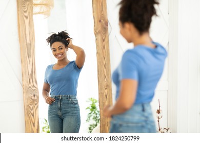 Female Beauty And Self-Confidence. Cheerful African Lady Posing Near Mirror After Slimming And Successful Weight Loss Standing At Home. Perfect Size Concept. Selective Focus