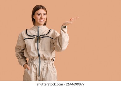 Female beekeeper in protective suit showing something on beige background