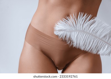 Female belly and soft feather. Concepts of body cosmetics and  hair removal treatment.