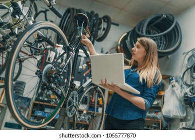 Female Bicycle Mechanic. Female mechanic with laptop. Sport, business and technology. Female mechanic in bicycle store - Powered by Shutterstock