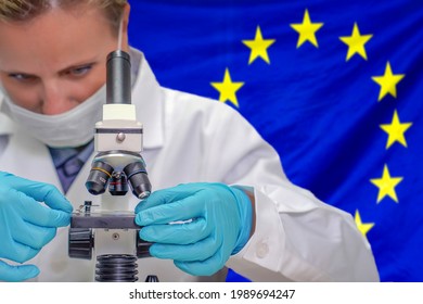 Female biochemist looking through a microscope against European Union flag background. Medical technology and pharmaceutical research and development of science concept in EU - Shutterstock ID 1989694247