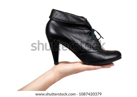 Female black leather high heel shoes with hand isolated on white background.