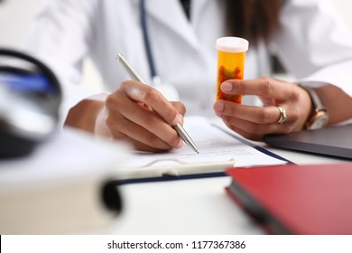 Female Black Medicine Doctor Hand Hold Jar Of Pills And Write Prescription To Patient At Worktable. Panacea And Life Save, Prescribing Treatment Legal Drug Store Concept. Empty Form Ready To Be Used