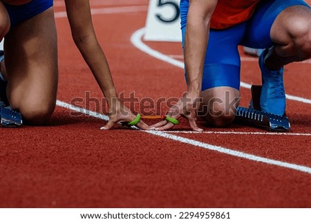 female blind para athlete runner with male guide in starting blocks ready running race, summer para athletics championships