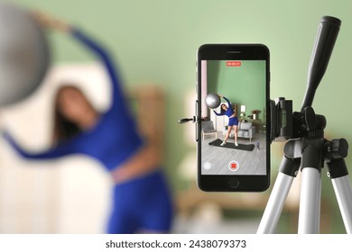 Female blogger recording sports video on screen of mobile phone at home, closeup - Powered by Shutterstock