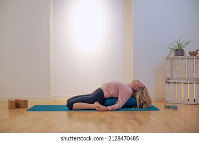 Female Blond Yoga Teacher Doing Eka Pada Rajakapotasana Or Pigeon Pose On Mat Indoors Yoga School