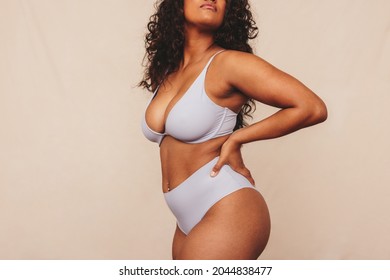 Female body in blue underwear. Anonymous young woman embracing her natural body and curves against a studio background. Confident young woman feeling positive and comfortable in her body.