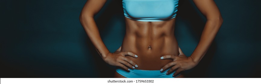 Female Body With Perfect Abs. Fit Girl With Six Pack Isolated on Dark Background. Healthy Active Lifestyle. Sportive Life. Panoramic Photo.