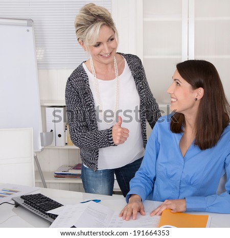 Female boss praise her young assistant in the office.