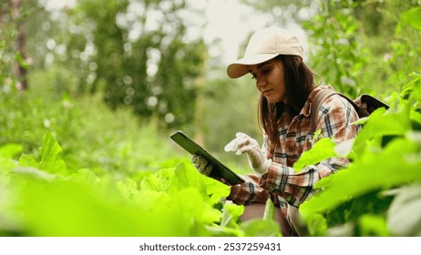 A female botanist researches plant species and works on a digital tablet in the rainforest. Environment and ecosystem concept. Biological activist. - Powered by Shutterstock