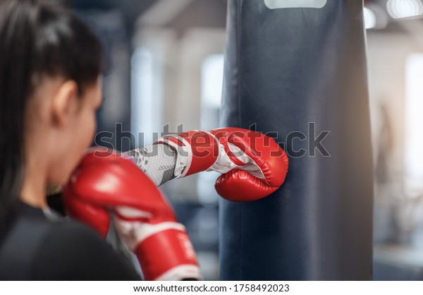 Female boxer in gloves hitting big\
punching ball during self defence class at gym, copy\
space