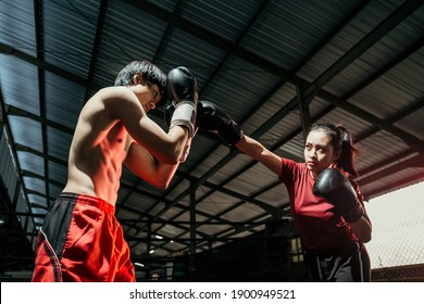 Female Boxer With Jab Motion While Competing Against Male Boxer At Boxing Camp