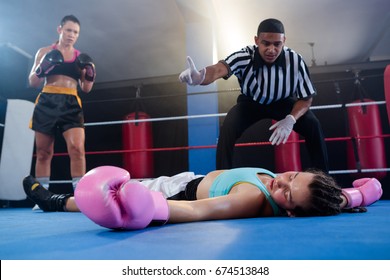 Female boxer looking while referee counting by athlete in boxing ring - Powered by Shutterstock