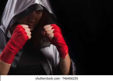 Female boxer makes a fight with a shadow, silver boxing robe and red boxing wraps, black background with copy space. Strong and confident, she will be a champion. - Powered by Shutterstock