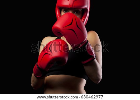 Female boxer in a self-defense posture on black background