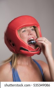 Female Boxer Wearing A Safety Head Guard And Inserting A Gum Shield Into Her Mouth