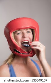 Female Boxer Wearing A Safety Head Guard And Inserting A Gum Shield Into Her Mouth