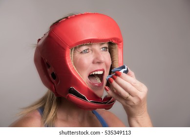 Female Boxer Wearing A Safety Head Guard And Inserting A Gum Shield Into Her Mouth