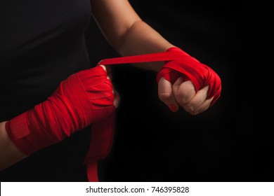 Female boxer is wrapping hands with red wrap, black background with copy space. Strong, ready for fighting or sparring. Women self defense. - Powered by Shutterstock