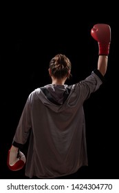 Female in boxing robe and red boxing glove on dark background.
