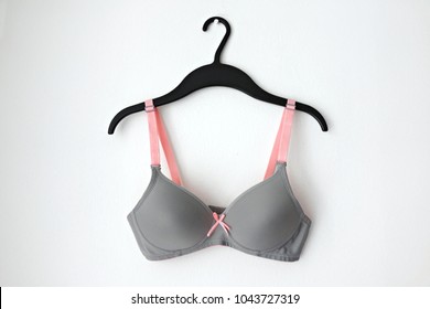 Female bra with pink ribbon on hanger, white background