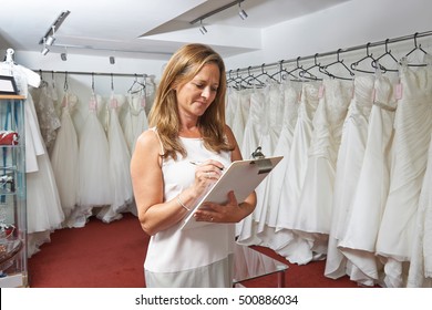 Female Bridal Store Owner With Wedding Dresses