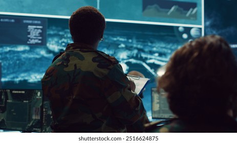 Female brigadier general gather intelligence reports on a big screen, ensuring national safety. Overseeing planning and coordination for a special mission, military reconnaissance system. Camera A. - Powered by Shutterstock