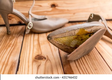 Female Broken High Heel Shoes On Wood Background