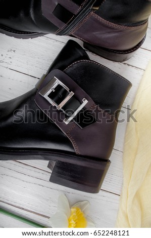 Female brown boots on a white wooden background. Trending autumn / spring boots for women with thick soles heels. Women's leather boots to cold weather. 
