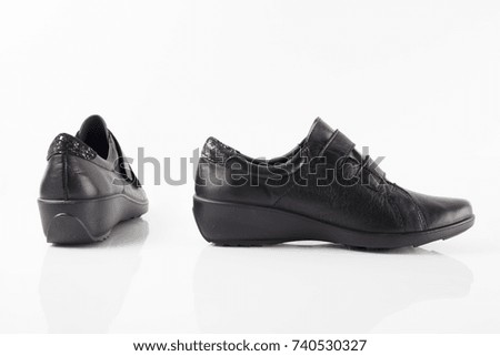 Female brown leather shoe on blue background, isolated product, comfortable footwear.