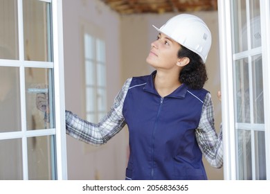 Female Builder In A White Helmet Opens A Window