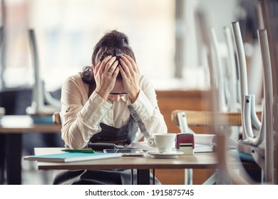 Female Busines Owner Holds Her Head In Hands In Desperation Over Paperwork And Tax Declaration In A Closed Pub.