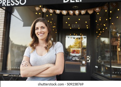 Female Business Owner Stands Outside Cafe With Arms Crossed