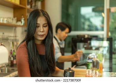 Female Business Owner Works With Her LGBT Partner To Prepare Coffee Or Drink For Customer In A Coffee Shop. A Couple Of LGBT Startup Help Each Other At A Coffee Counter For Their Business.