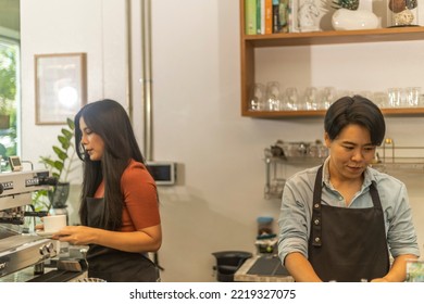 Female Business Owner Works With Her LGBT Partner To Prepare Coffee Or Drink For Customer In A Coffee Shop. A Couple Of LGBT Startup Help Each Other At A Coffee Counter For Their Business.