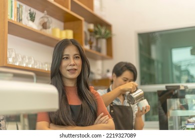 Female Business Owner Works With Her LGBT Partner To Prepare Coffee Or Drink For Customer In A Coffee Shop. A Couple Of LGBT Startup Help Each Other At A Coffee Counter For Their Business.