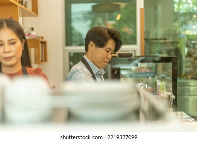 Female Business Owner Works With Her LGBT Partner To Prepare Coffee Or Drink For Customer In A Coffee Shop. A Couple Of LGBT Startup Help Each Other At A Coffee Counter For Their Business.