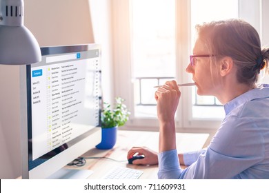 Female business person reading email on computer screen at work on internet