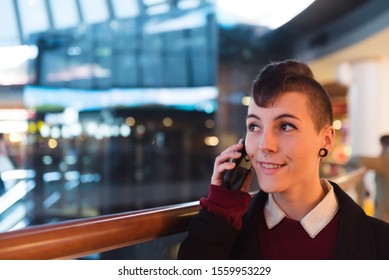 Female businesswoman with curly hair and modern style answers a call in a mall.