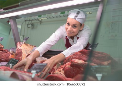 Female Butcher Arranging Window In Store