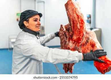 Female butcher carrying the hanging cut pieces of cattle in a meat factory - Powered by Shutterstock