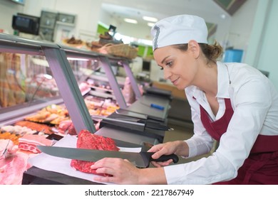 A Female Butcher Cuts Meat