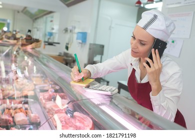 female butcher talking on the phone with customer - Powered by Shutterstock