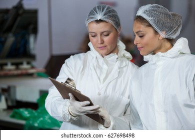 Female butchers discussing over clipboard at meat factory - Powered by Shutterstock