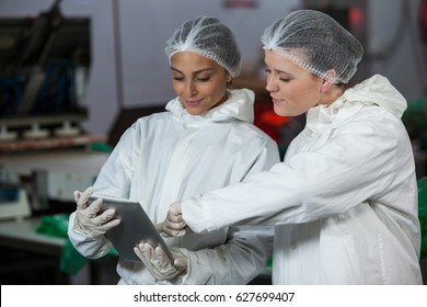 Female butchers discussing over digital tablet at meat factory - Powered by Shutterstock