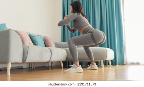 female butt workout squats at home. Athletic Woman squats workout in living room. Female gymnastics. Glutes workout motivation. Fitness at home concept.