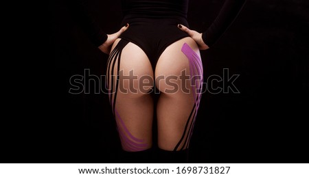 Female buttocks with physio tape on black background