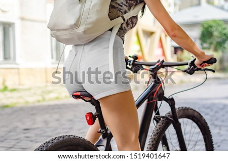 Female buttocks in white shorts on a bicycle saddle on a road trip.