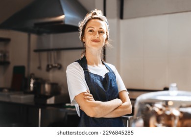 Female cafe owner, showing confidence in her small business, stands in front of the camera with arms crossed. Woman wearing an apron, proudly displays her role as a hospitality entrepreneur. - Powered by Shutterstock