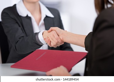 Female candidate shaking hands with businesswoman at desk in office